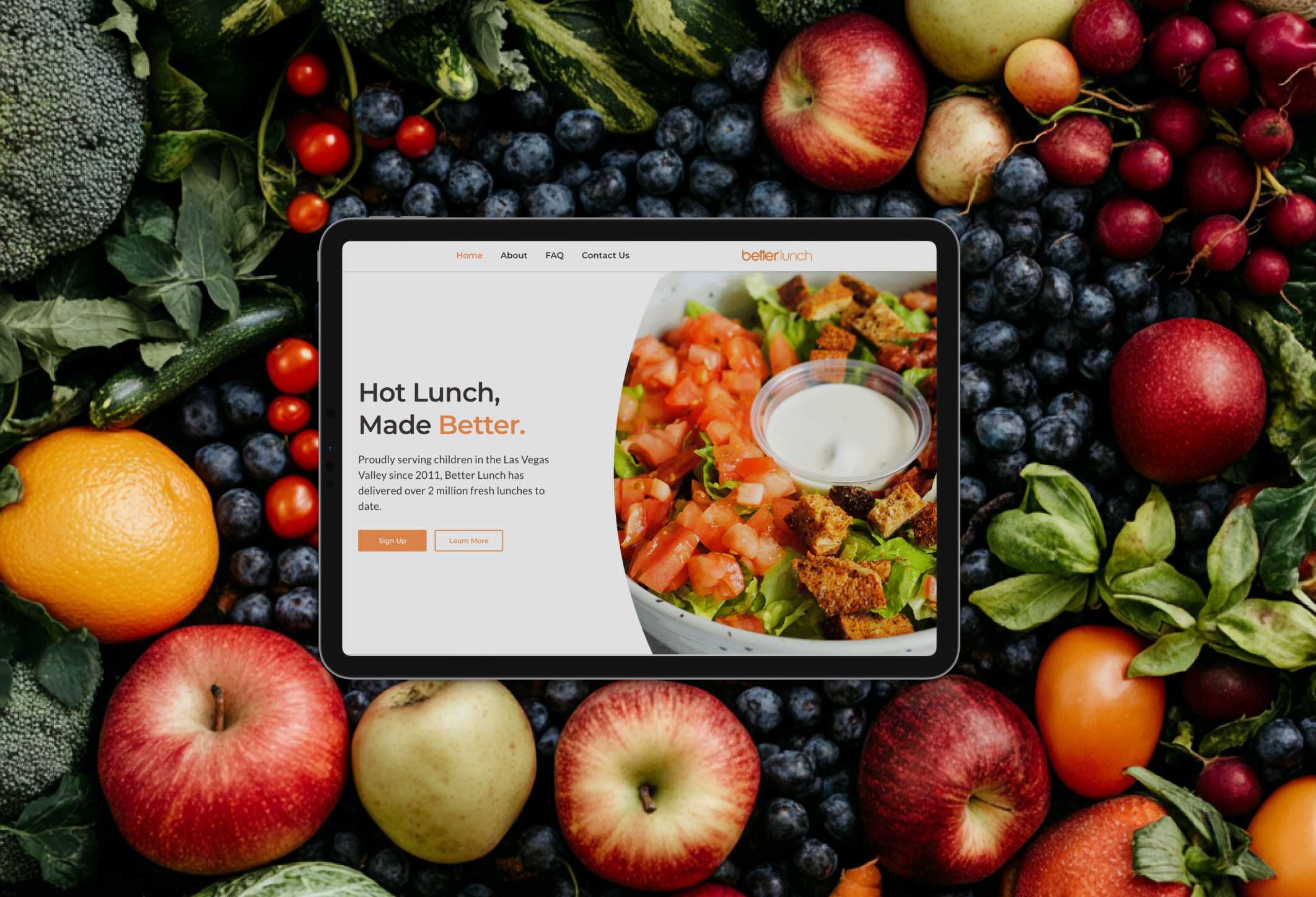 tablet with betterlunch's website open sitting on top of fruit and vegetables background